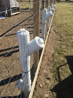 the fence is made of wood and has white plastic pipes attached to it, along with other fences