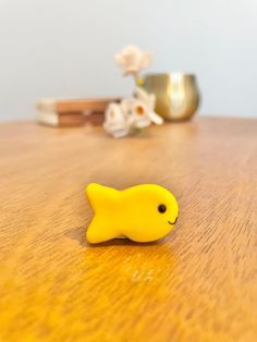 a yellow toy fish sitting on top of a wooden table