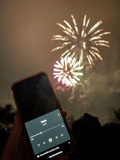 someone holding up their cell phone to take a picture of fireworks