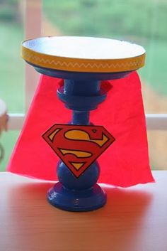 a blue candle holder with a superman symbol on it and a red flag in the background