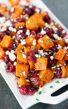 a white plate topped with sweet potatoes, cranberries and feta cheese on top