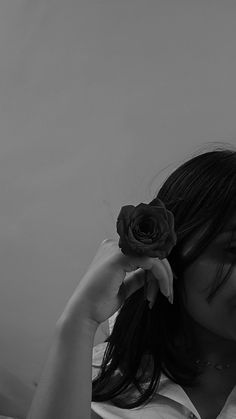 black and white photograph of a woman holding a rose in her hair with one hand