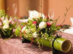 two vases filled with flowers sitting on top of a pink table cloth covered table