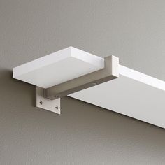 a white light fixture mounted on the side of a wall with a square shaped object attached to it