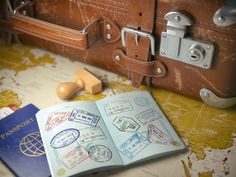 an open passport sitting on top of a map next to a piece of leather luggage