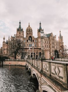 an old building is next to the water in front of a bridge and some buildings