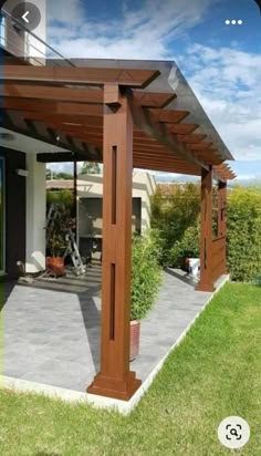 a wooden pergola sitting on top of a lush green field next to a building