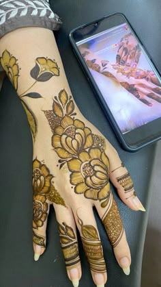 a woman's hand with henna tattoos on it and a phone in the background