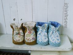 three baby booties are lined up on a shelf with white boards in the background