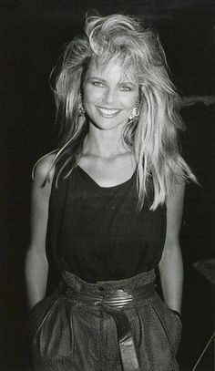 a black and white photo of a woman with long blonde hair wearing a short skirt