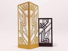 two decorative boxes with designs on them, one is gold and the other is black