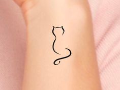 a small black cat tattoo on the left wrist and right arm, it looks like an animal