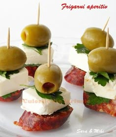 small appetizers with olives, cheese and meat on them sitting on a white plate