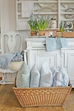 a basket filled with lots of pillows sitting on top of a wooden floor next to a table