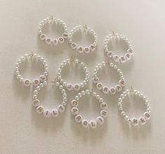 six pairs of pearl hoop earrings on a white tablecloth with the word love spelled in gold letters