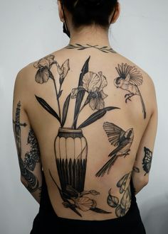 a woman with tattoos on her back has flowers in a vase and birds flying around