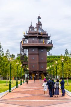 several people are standing in front of a tall building with a clock on the top