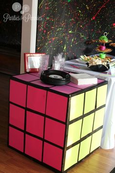 a rubik cube is sitting on the floor in front of a table with food