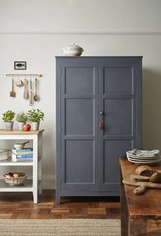 a blue cabinet sitting in the corner of a room next to a table with plates and bowls on it