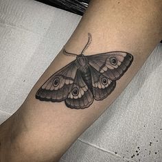 a small butterfly tattoo on the right forearm and leg, with an eyeball in the center