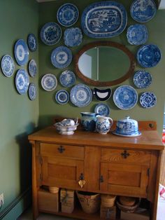 a wooden cabinet with plates on it and a mirror above the dresser in front of it