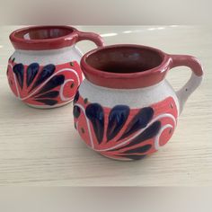 two red and white vases sitting on top of a table