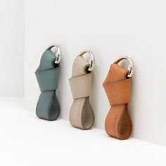 three different colored leather key chains hanging from hooks