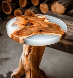 a table made out of wood and glass on top of cement floor next to stacks of logs