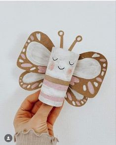 a hand holding up a paper butterfly with scissors on it's back and eyes closed