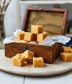 a wooden box filled with cubes of cheese on top of a white plate next to a window