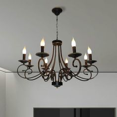 a chandelier with five lit candles hanging from it's center point in an empty room