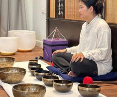 a woman sitting on top of a table filled with bowls