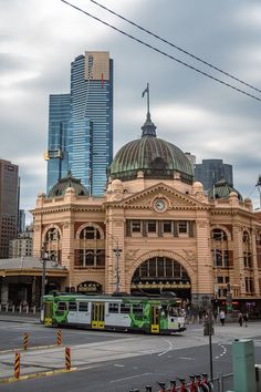 an old train station in the city with two green and yellow buses parked outside it