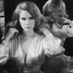 black and white photograph of a woman in front of a mirror with her hands on her hair