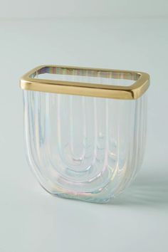 a glass vase with a gold rim on a white surface, in the shape of a bowl