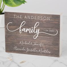 a wooden sign that says the anderson family on it and is next to a potted plant