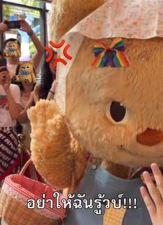 a large teddy bear wearing a hat and holding his hand up in front of him