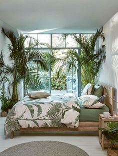 a bed sitting in a bedroom next to a window with lots of plants on it