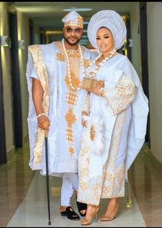 a man and woman dressed in traditional african clothing posing for the camera with a cane