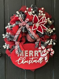 a christmas wreath with candy canes and bows hanging on the front door to say merry christmas