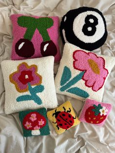 four decorative pillows on a bed with flowers and ladybug's face in the middle