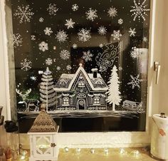 a window with snowflakes on it and a christmas scene in the window sill