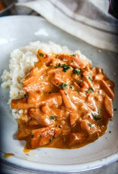 a white plate topped with rice and meat covered in gravy on top of it