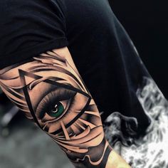 a person with a tattoo on their arm that has an eye and triangle in it