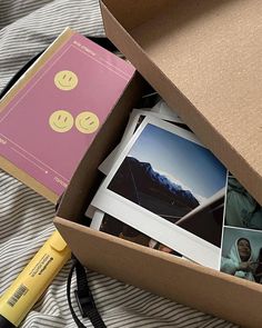 an open box with pictures and a pen in it on top of a striped blanket