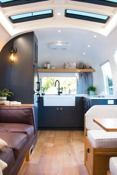 the interior of a tiny home with wood flooring and white walls, windows, and dark blue cabinets