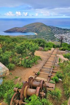 an old train track with rusted wheels on it near the ocean and mountains in the background