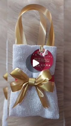 a white bag with a gold bow on it and a red heart in the middle