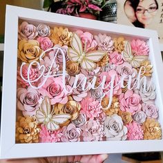 a person holding up a framed photo with flowers in the frame and butterflies on it