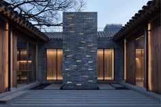 an outdoor courtyard is lit up with lights and stone walls, along with wooden benches